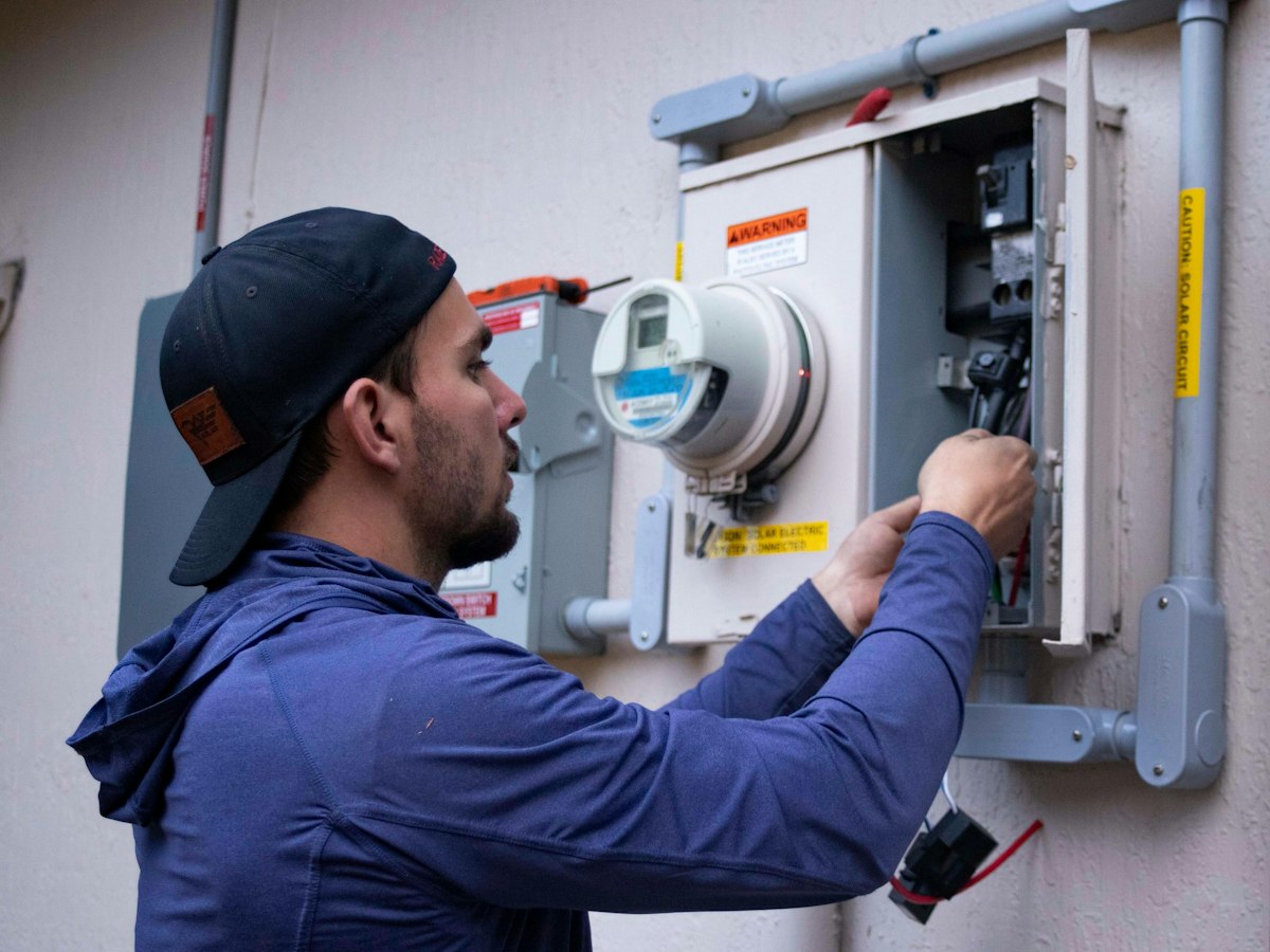An electrician working on a wall mounted electricity meter
