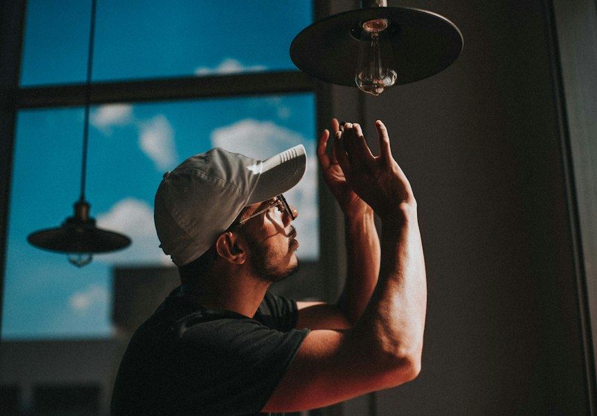 An electrician working on a ceiling light fitting